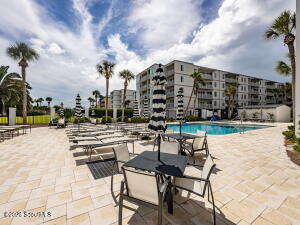 Ocean-view condominium at North Breakers, 1470 Wood Ave on St. Simons Island — multi-story building with a pool deck, lounge chairs and palm trees
