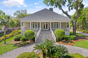 Single-story coastal cottage at 234 McIntosh Ave with a full-width front porch, white columns, and landscaped yard — marsh view home on St. Simons Island, GA